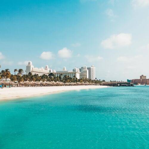 Lichtblauw water, palmbomen en wit zand bij Palm Beach in Aruba