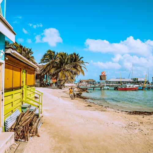 Gekleurde houten hutten en palmbomen staan langs het strand van Ambergris Caye in Belize