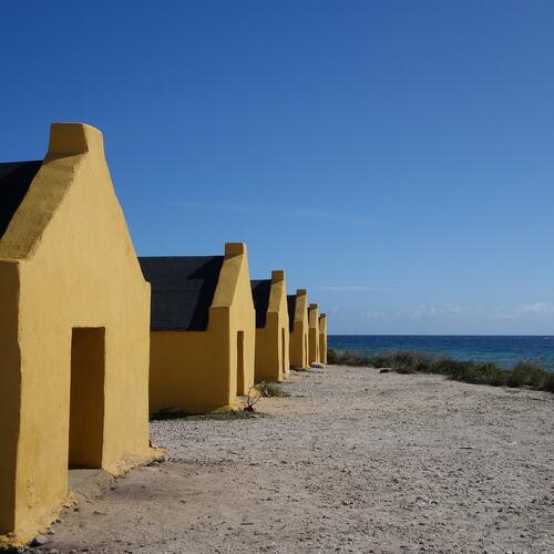 Een rij van gele huisjes aan het strand in Bonaire