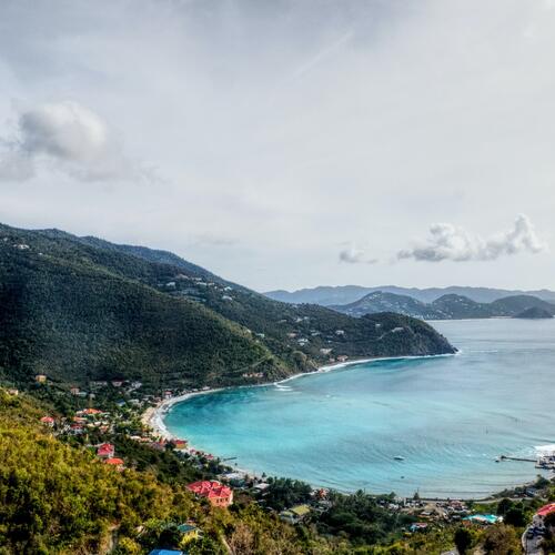 Een zicht vanuit de heuvels op het lichtblauwe water van Cane Garden Bay op Tortola in de Britse Maagdeneilanden