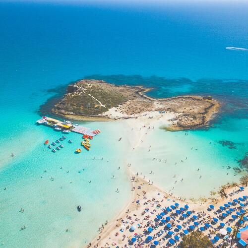 Een strand bedekt door blauwe parasols loopt uit op een eiland in Ayia Napa in Cyprus