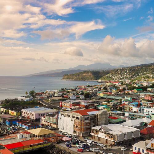 Een luchtfoto van de gekleurde huizen in Roseau, de hoofdstad van Dominica, met de zee en de bergen in de achtergrond