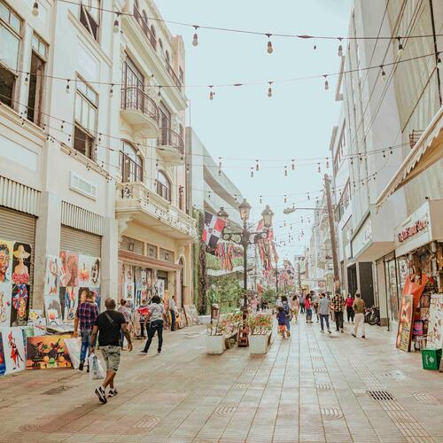 Mensen wandelen door een winkelstraat waar schilderijen verkocht worden in Santo Domingo, Dominicaanse Republiek