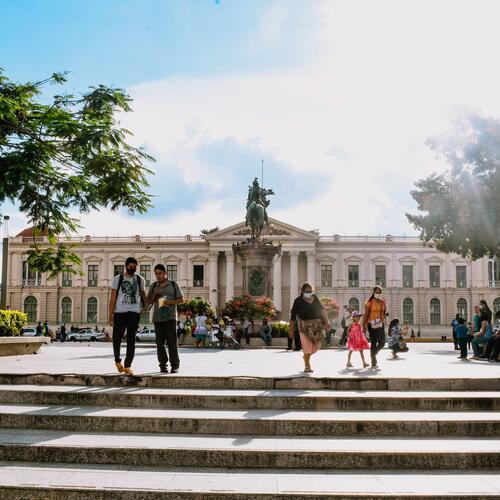 Mensen wandelen op de Plaza Gerardo Barrios met op de achtergrond het Palacio Nacional in San Salvador