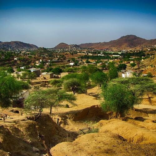 Aan de rand van de kleine stad Ghinda wisselen groene bomen en kleine huisjes elkaar af tussen de heuvels