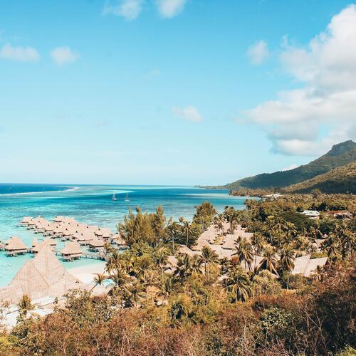 Hutjes staan langs steigers in het lichtblauwe water van Bora-Bora