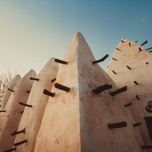 Houten balken steken uit de witte muren van de oude Larabanga-moskee in Ghana