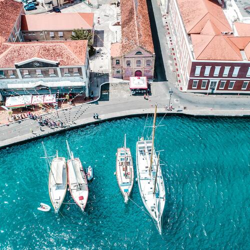 Boten liggen langs een kade met vlaggetjes boven de straat en Georgiaanse gebouwen in Saint George
