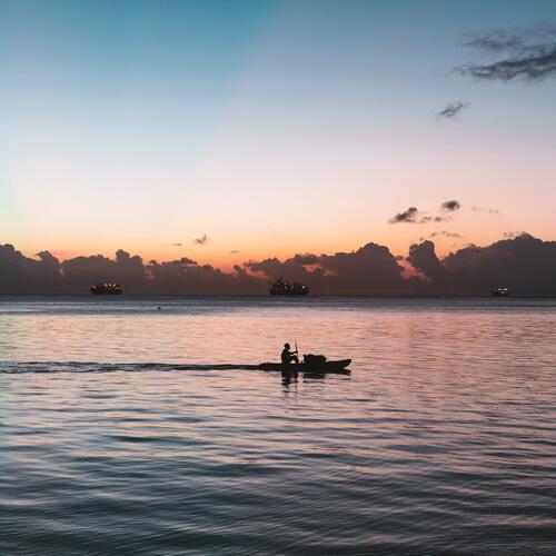Een bootje met roeier vaart voorbij de horizon op de zee in Saipan.