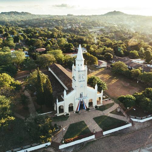 Witte kerk en omringen groen landschap in de hoofdstad Asuncion.
