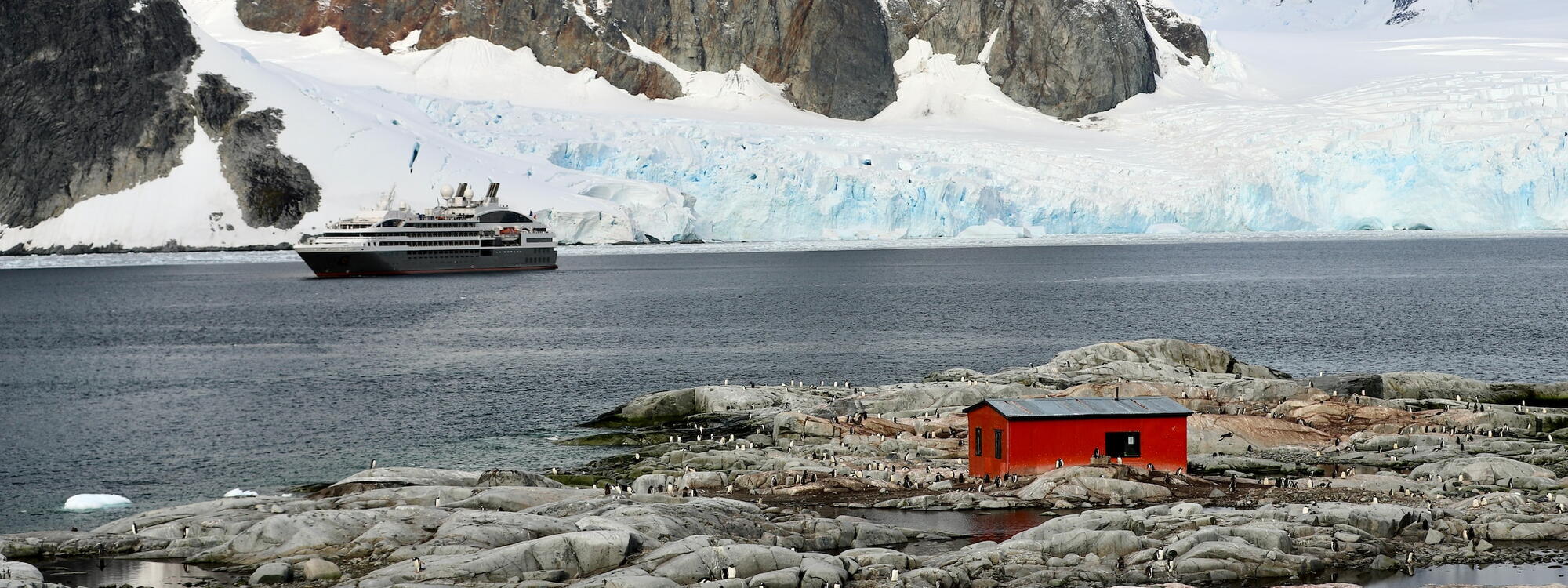 Cruiseschip Le Boreal aan de kust van Antarctica bij een rode hut