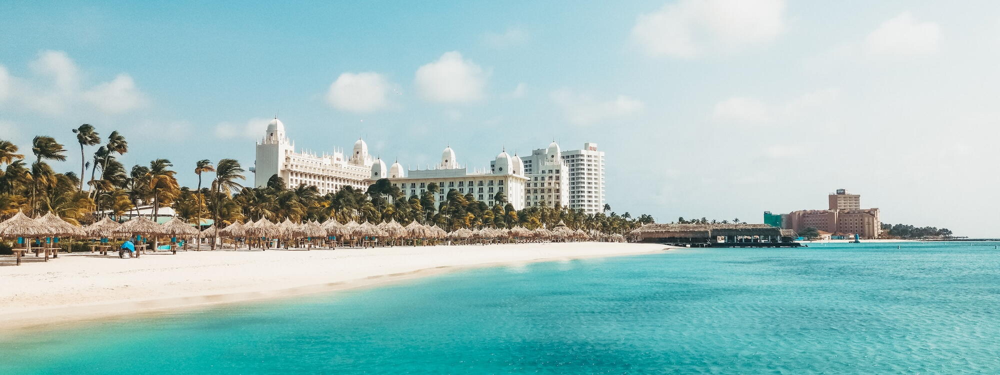 Lichtblauw water, palmbomen en wit zand bij Palm Beach in Aruba
