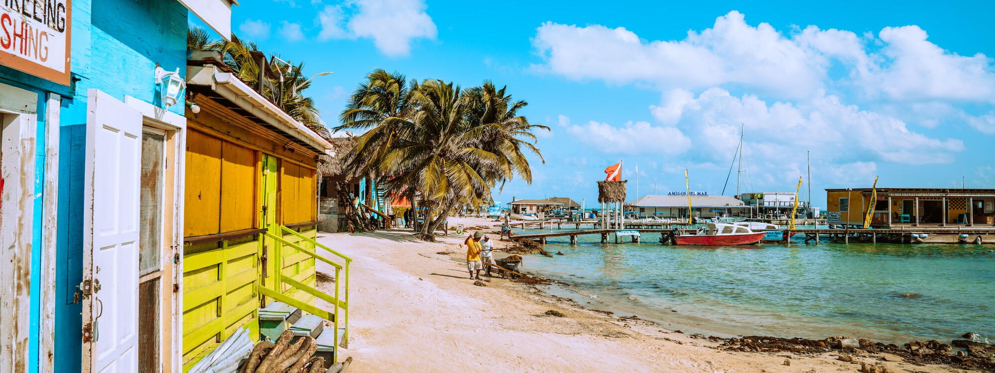 Gekleurde houten hutten en palmbomen staan langs het strand van Ambergris Caye in Belize