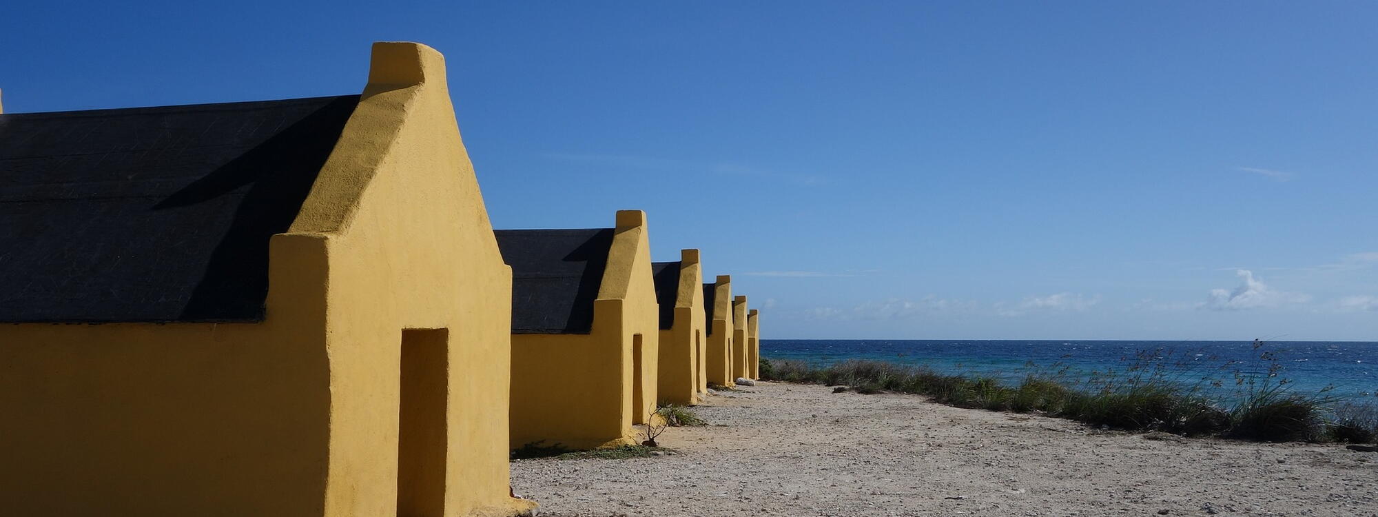 Een rij van gele huisjes aan het strand in Bonaire