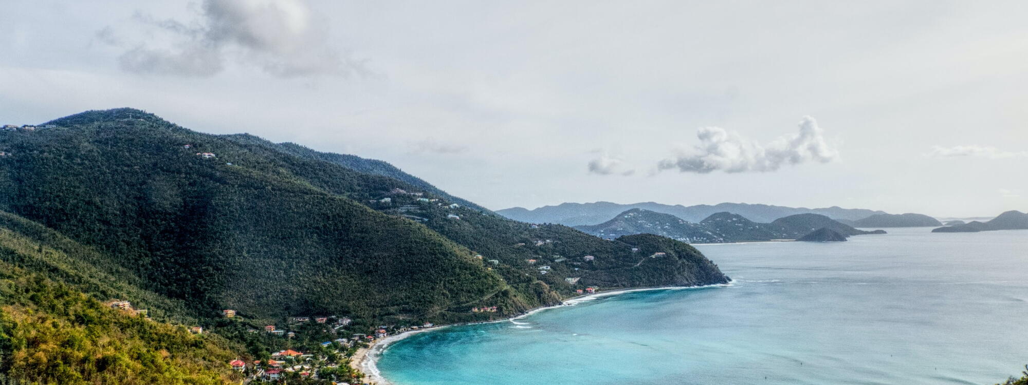 Een zicht vanuit de heuvels op het lichtblauwe water van Cane Garden Bay op Tortola in de Britse Maagdeneilanden