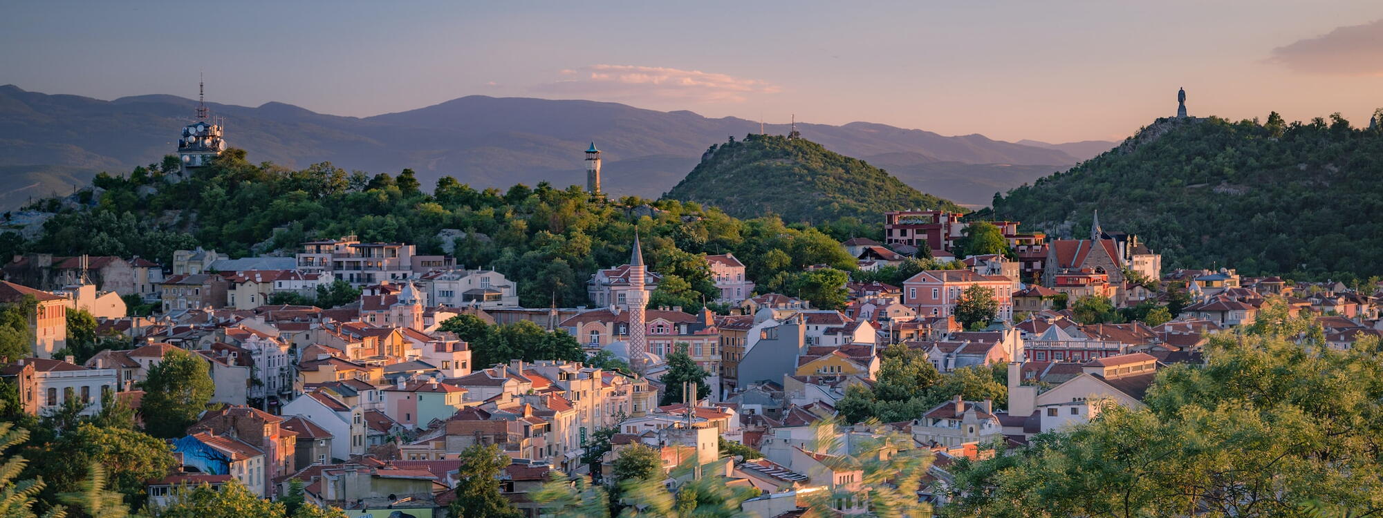 Torens van kerken en moskeeën boven de daken van Plovdiv, een stad tussen de groene heuvels in Bulgarije