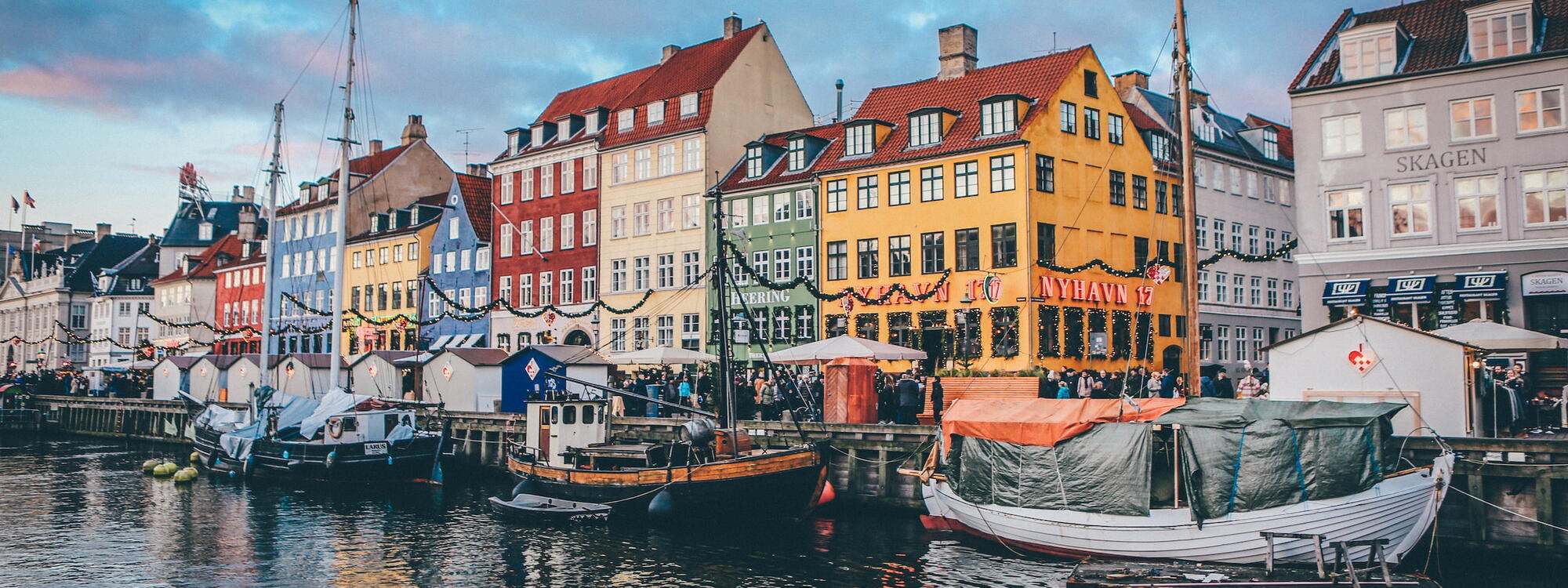 Boten liggen aangemeerd voor de gekleurde huizen van Nyhaven in Copenhagen