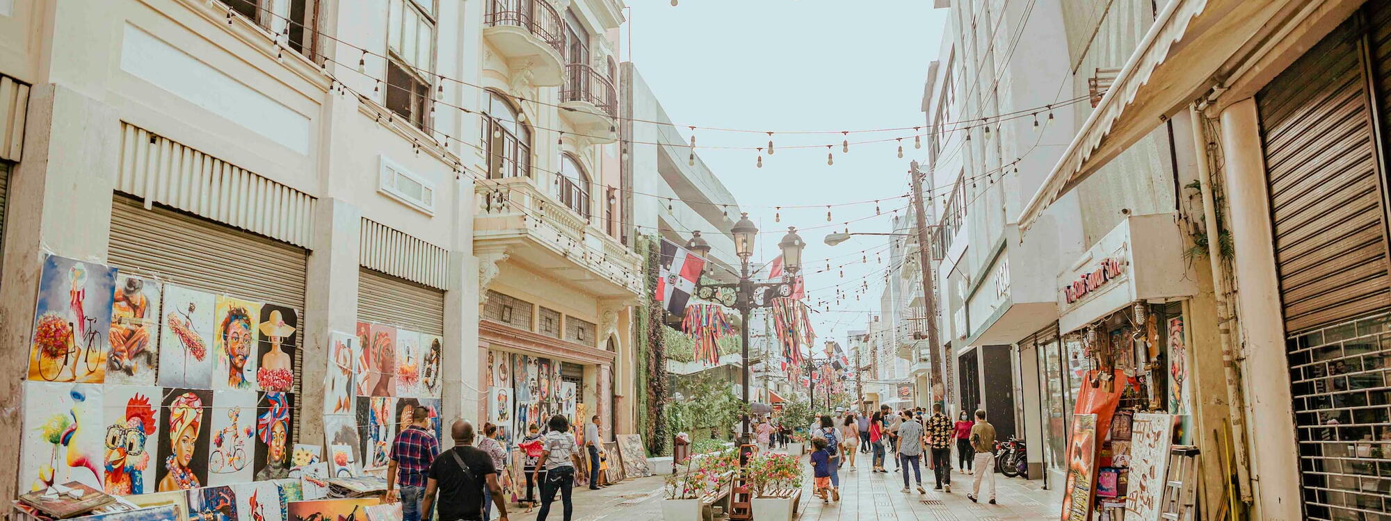 Mensen wandelen door een winkelstraat waar schilderijen verkocht worden in Santo Domingo, Dominicaanse Republiek