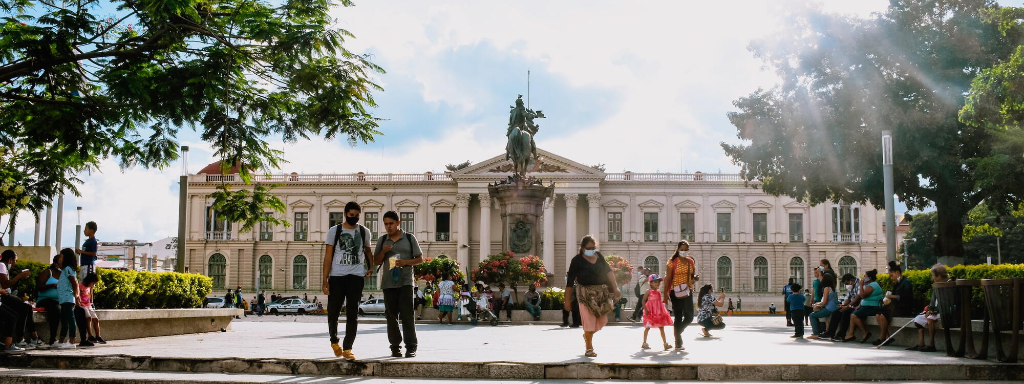 Mensen wandelen op de Plaza Gerardo Barrios met op de achtergrond het Palacio Nacional in San Salvador