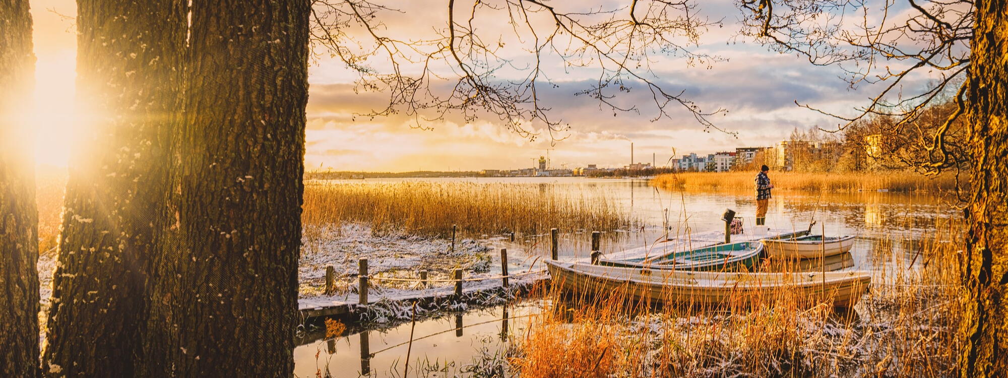 Een man staat op een kleine steiger met bootjes aan de rand van het besneeuwde Helsinki