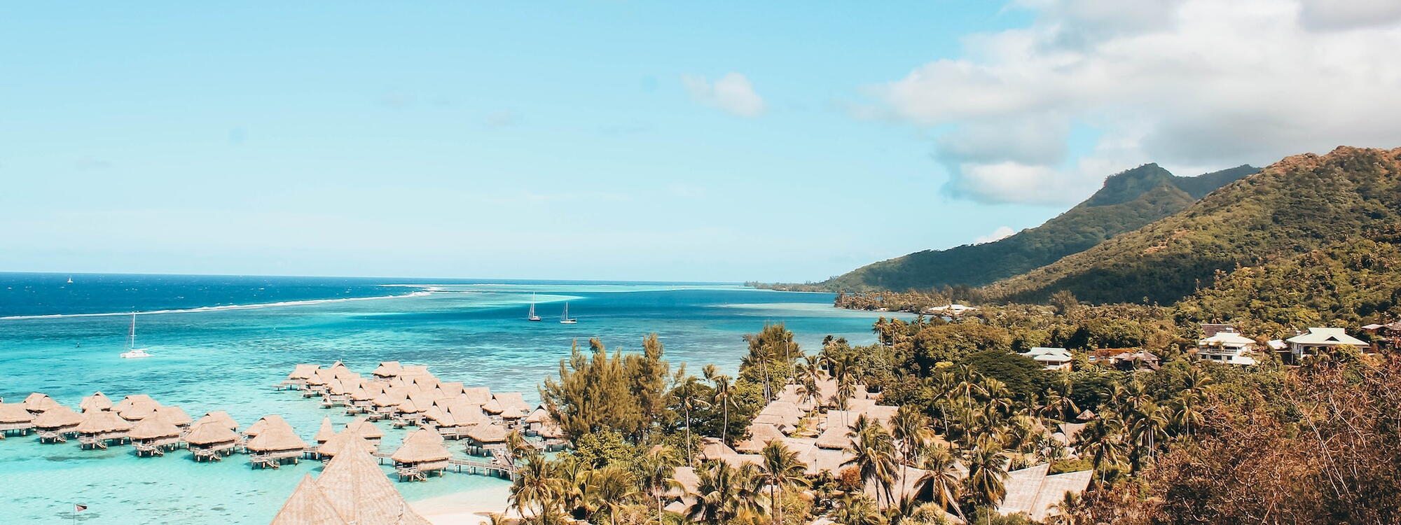 Hutjes staan langs steigers in het lichtblauwe water van Bora-Bora