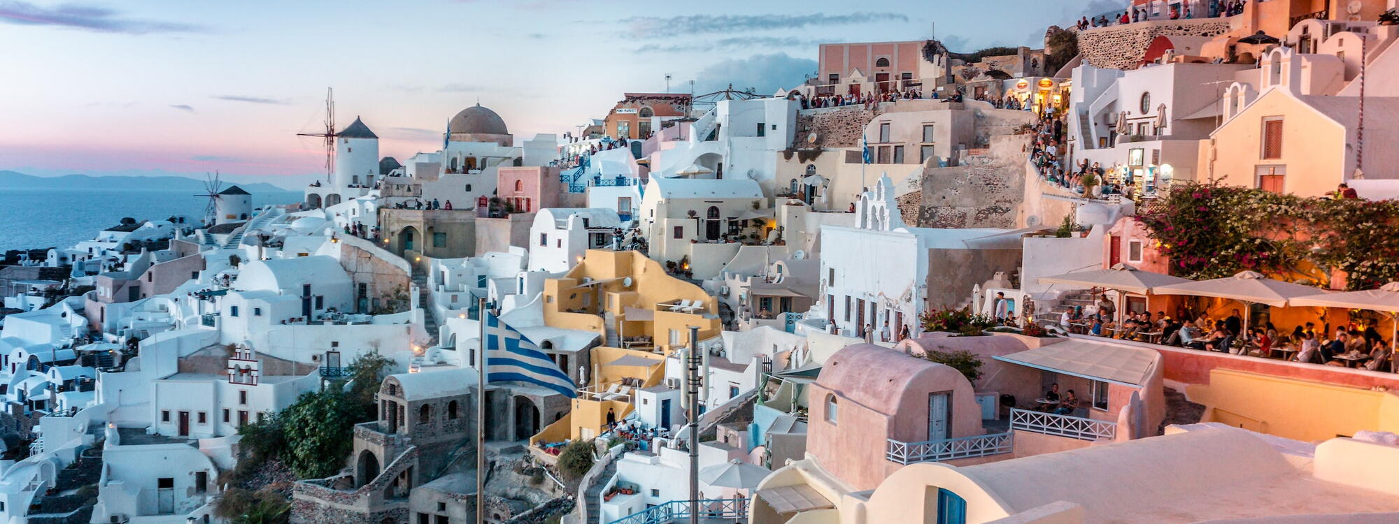 Witte huisjes worden afgewisseld door roze, gele en oranje huisjes op het eiland Santorini in Griekenland