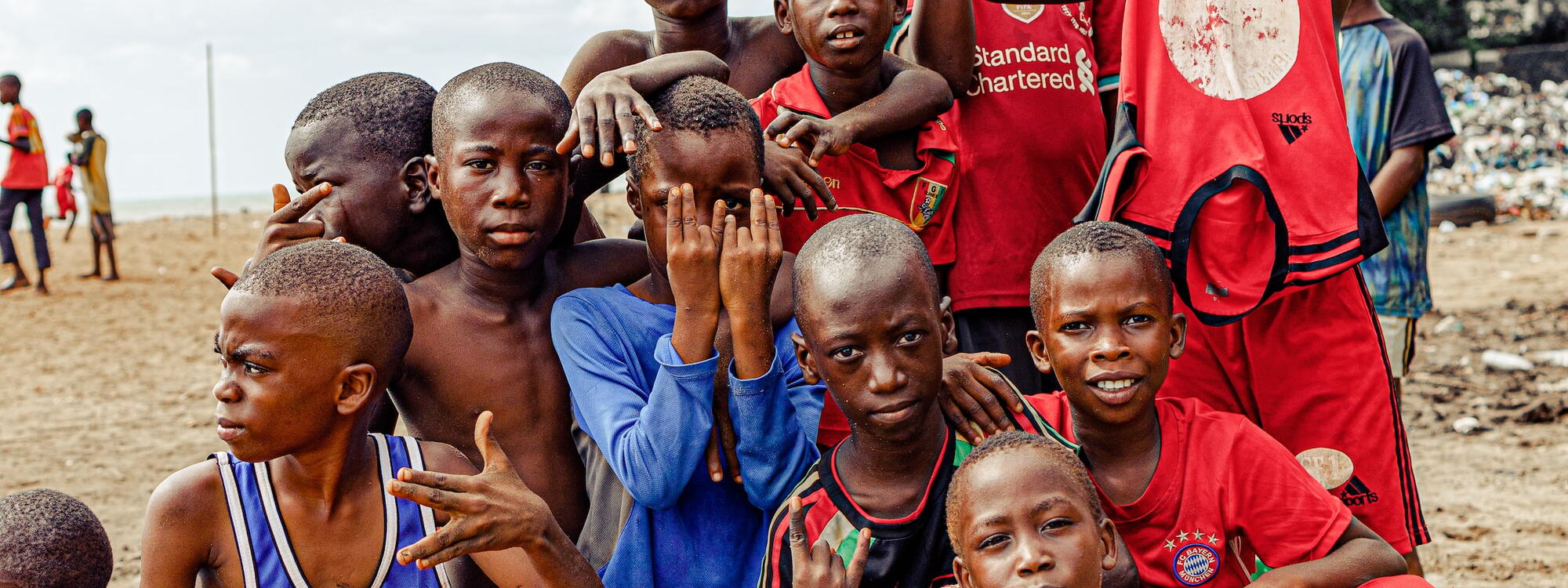 Kinderen in voetbaloutfit maken handgebaren terwijl ze poseren voor een foto in Conakry, Guinee