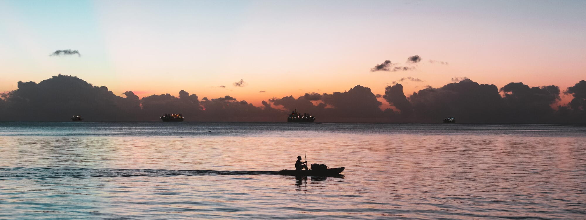 Een bootje met roeier vaart voorbij de horizon op de zee in Saipan.
